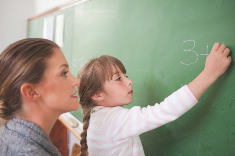 Girl at chalkboard with teacher